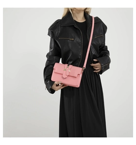 Detail of pink faux leather crossbody bag with gold metal buckle on model