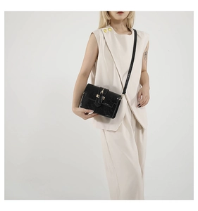 Detail of glossy black crocodile texture on shoulder bag with golden hardware