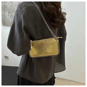 Close-up of metallic gold handbag with silver stud trim and a fine chain strap