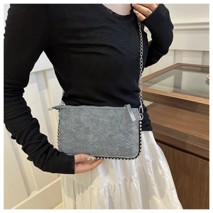 Detail of gray crossbody bag with vintage texture and silver bead trim along the edges