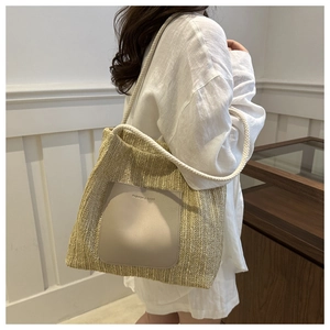 Detailed view of beige woven tote bag with rope handles and leather pocket decoration