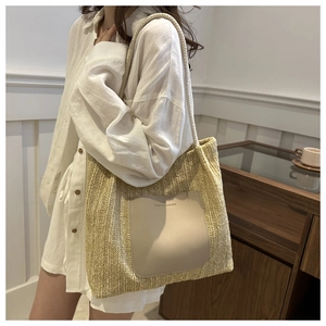 Close-up of woven straw tote bag with beige leather pocket and fashion embossed text