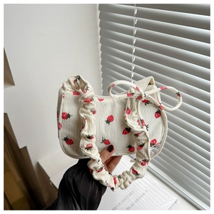 Détail de la texture velours et imprimé fraise sur sac blanc avec bandoulière à volants