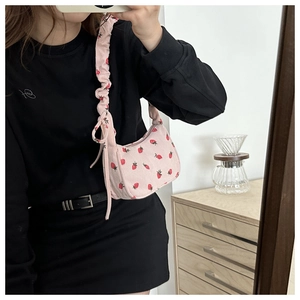Detail of pink corduroy shoulder bag featuring strawberry print and ruched strap