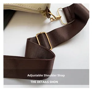 Detail of adjustable wide fabric strap with gold metal buckles on a white textured handbag