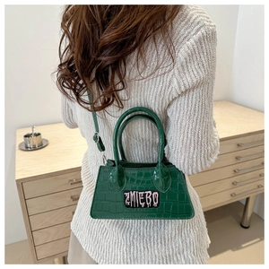 Detail of dark green crocodile texture bag with pink graffiti embroidery on beige knitwear