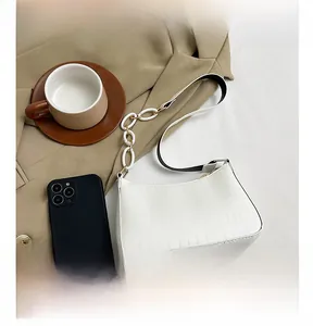 Detail of white crocodile pattern shoulder bag with link chain on a brown blazer
