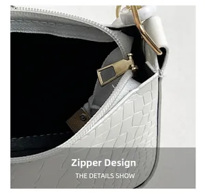 Macro shot of gold metal zipper and black fabric lining on white croc-embossed bag