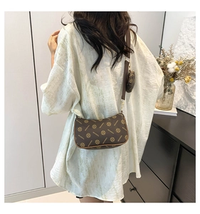 Detail of a brown monogram crescent crossbody bag with a round mini coin purse pouch