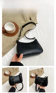 Close-up of black crocodile-embossed crescent underarm bag with black resin chain