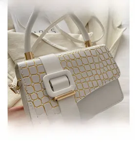 Detail of white handbag featuring gold crocodile embossed texture and metal buckle