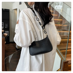 Close-up of black crocodile-embossed leather handbag with metallic buckle and strap details