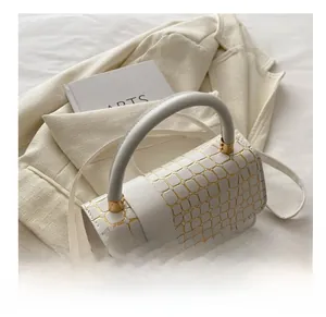 Detail view of white luxury handbag with gold crocodile texture on casual suit jacket