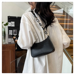 Close-up of black crocodile pattern faux leather underarm bag with metal chain strap