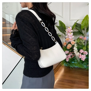 Detail of white baguette bag with crocodile pattern and stylish acrylic chain strap
