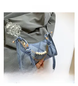 Dettaglio borsa hobo in denim blu con patchwork, catena di perle e manico annodato
