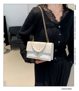 Détail du sac bandoulière avec poignée en perles, chaîne et texture tissée sur cuir écru