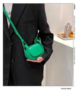 Close-up of bright green mini saddle bag with matte leather and adjustable strap