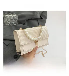 Détail du sac à bandoulière blanc crème avec poignée en perles et chaîne dorée chic
