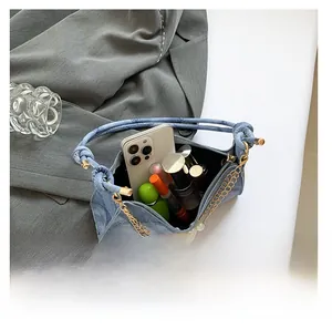 Dettaglio interno borsa in denim con catena di perle e manico con nodo