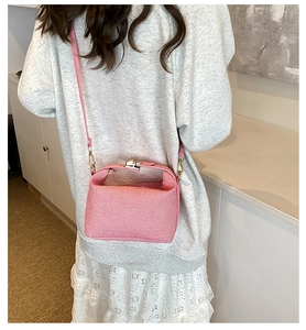 Pink textured crossbody bag with metal buckle shown being worn in home setting