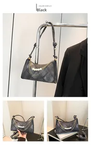 Dettaglio borsa baguette in denim nero trapuntato con catena dorata e perle bianche