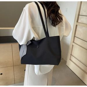 Detail of a large black tote bag with a stylish black and white checkered bow decoration