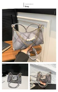 Dettaglio borsa a mezzaluna grigia con texture denim, perle e catene metalliche