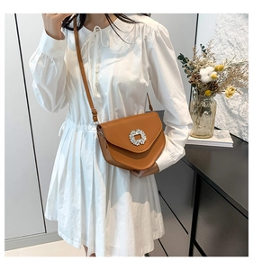 Gros plan du sac bandoulière marron avec boucle en strass brillante et bandoulière fine