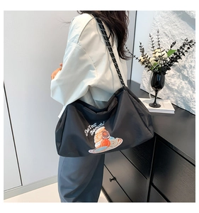 Détail du sac cabas en nylon noir avec broderie doughnut et bandoulière rayée
