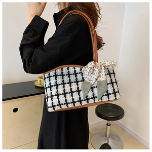 Detail of checkered tweed tote bag with brown leather handles and silk scarf accent