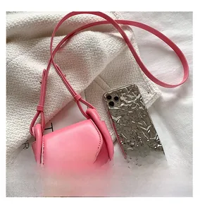 Pink leather mini saddle bag for kids shown next to a smartphone for size reference