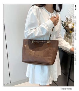 Detailed view of dark brown leather patchwork tote bag with gold chain shoulder strap