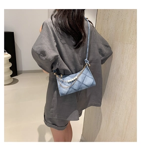 Dettaglio della borsa a tracolla in denim blu con trama trapuntata, perle e catena d'oro