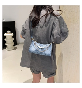 Dettaglio borsa trapuntata in denim azzurro con doppia catena e perle bianche decorative