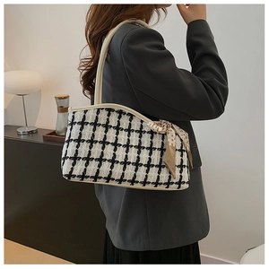 Detail of black and white houndstooth tweed tote bag with polka dot scarf and leather trim