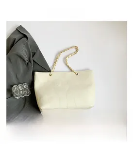 Detail of cream white tote bag featuring square patchwork texture and woven chain strap