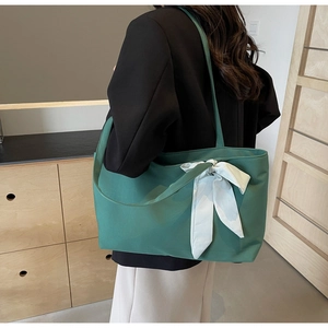 Detail of dark green large tote bag with a plaid bow tie decoration on shoulder