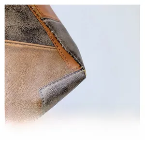 Close-up of contrast stitching on brown and grey textured leather shoulder bag