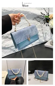 Détail du sac bandoulière bleu clair avec texture tissée et poignée en perles
