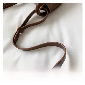 Close-up of a brown leather shoulder strap with golden metal buckle for kids handbag