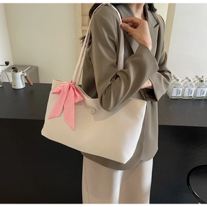 Modische beige Tragetasche mit rosa karierter Schleife auf der Schulter getragen