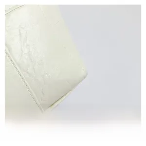 Detailed close-up of ivory stone-textured leather with precise stitching on a tote bag