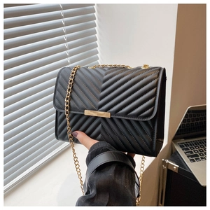 Detail of black chevron quilted PU leather flap bag with elegant gold chain and hardware
