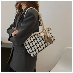 Détail d'un sac bandoulière en tweed à carreaux avec nœud en soie et sangle en cuir