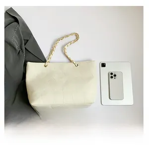 Close-up of beige tote bag showing geometric textured leather and gold chain strap detail