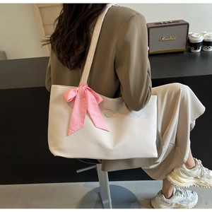 Detailed shot of white PU tote bag with a pink checkered bow on a model shoulder
