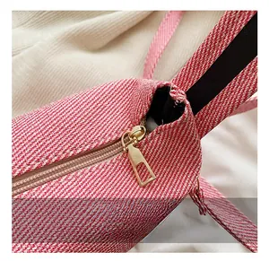 Detailed macro view of the golden rectangular zipper on a red and white striped fabric bag