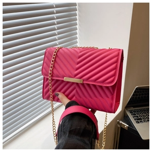 Detail of rose pink crossbody bag featuring V-shaped quilting and gold metal chain strap