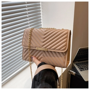 Close-up of beige quilted PU leather crossbody bag with V-shaped stitching and gold chain